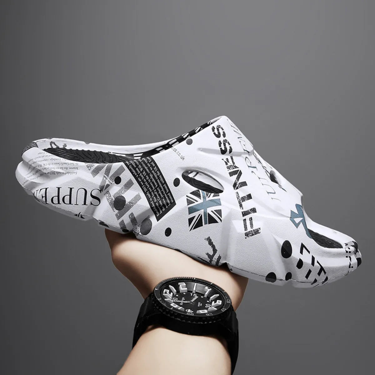 White graphic-print open-toe platform slide with oval side opening, held in a hand