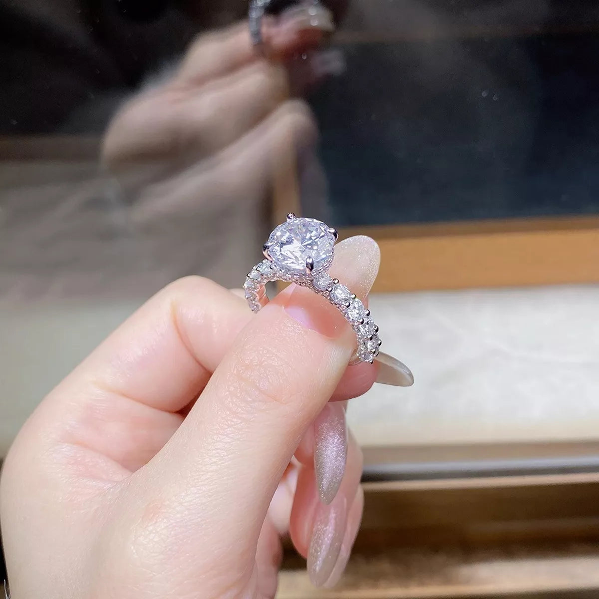 Side view of a round clear stone in a raised setting above a sparkling ring band.