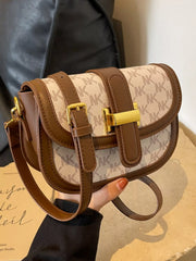 Close-up of cream patterned crossbody bag with brown trim, gold-coloured clasp and shoulder strap
