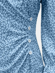 Close-up of blue dress's printed fabric and decorative buttons