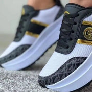 Close-up of black patterned panels and gold trim on platform sneakers