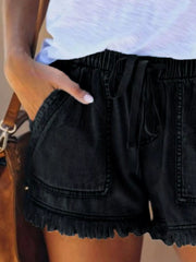 Close view of black drawstring denim shorts showing the gathered waist and front pockets