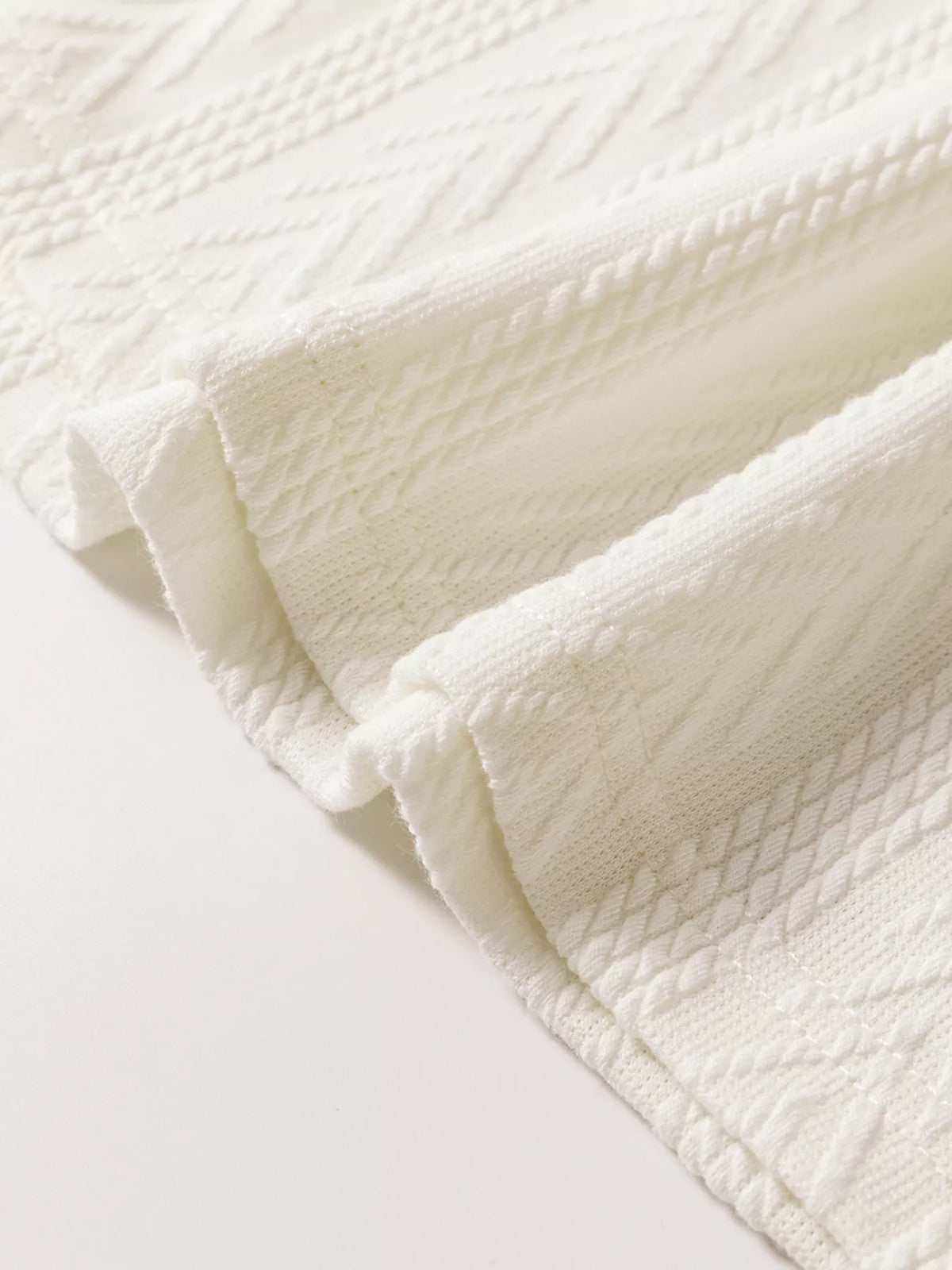 Close-up of raised knit texture on ivory blouse