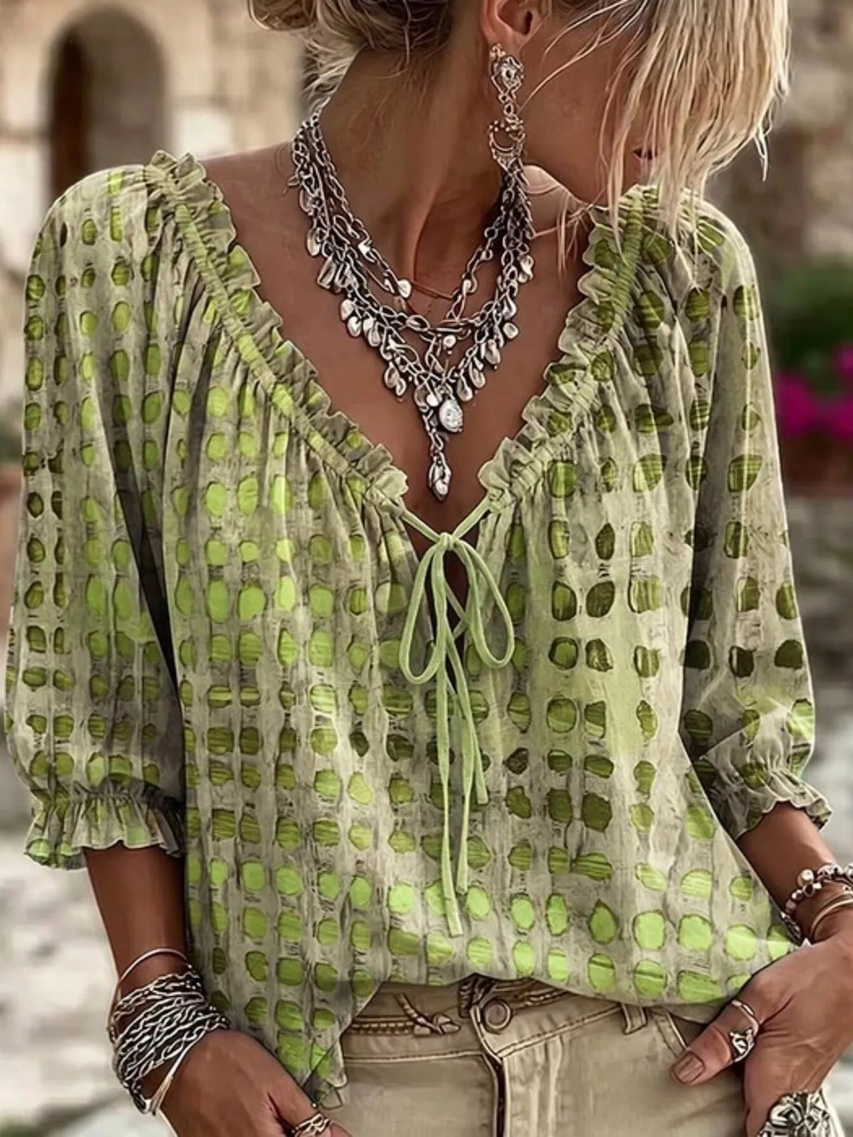 Green geometric-print ruffle-neck blouse worn with beige jeans, front view.