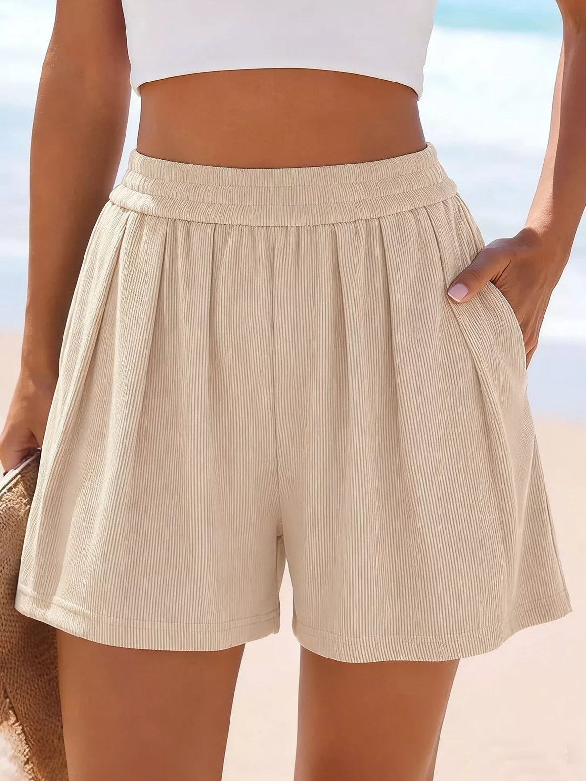 Front view of beige ribbed shorts with hand resting at the waistband