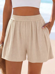 Front view of beige ribbed shorts with hand resting at the waistband