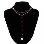 Gold-tone pearl station necklace with coin pendant on a black display bust