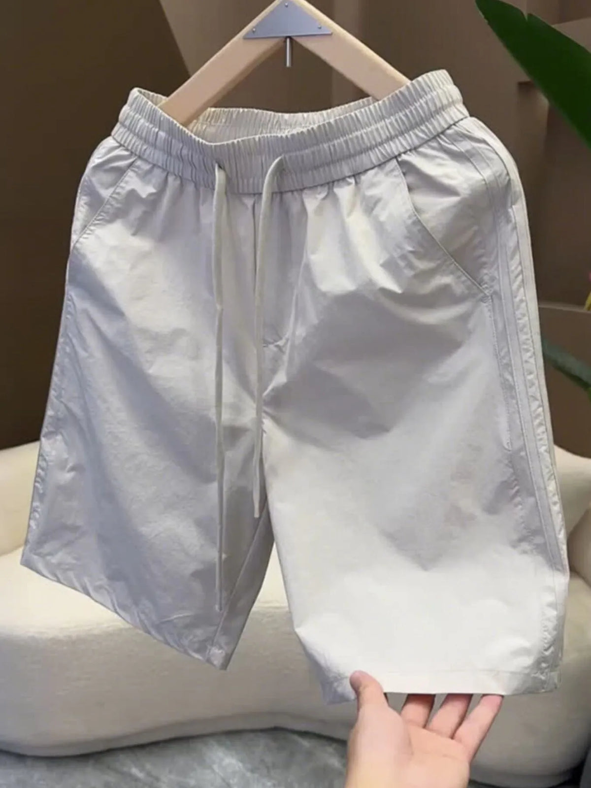 Light gray pocketed drawstring shorts hanging on a hanger