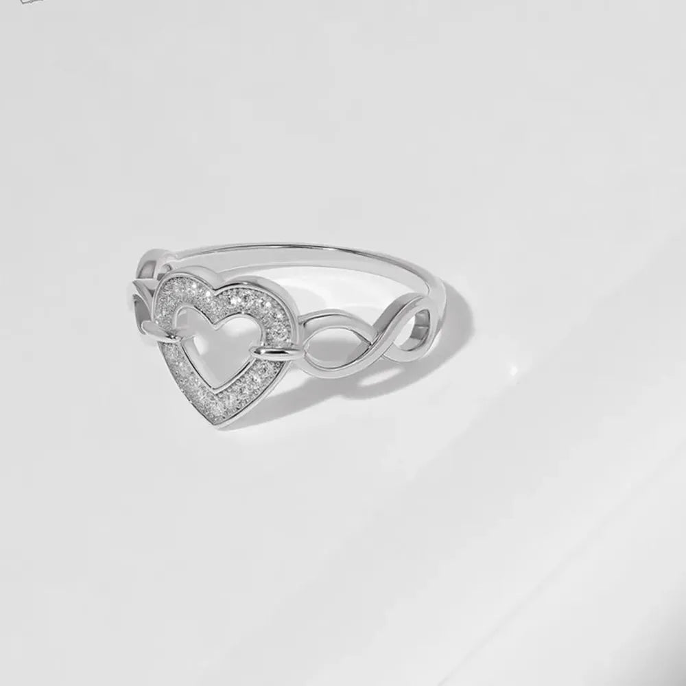 Silver-tone open-heart ring showing the crystal border and infinity-style band