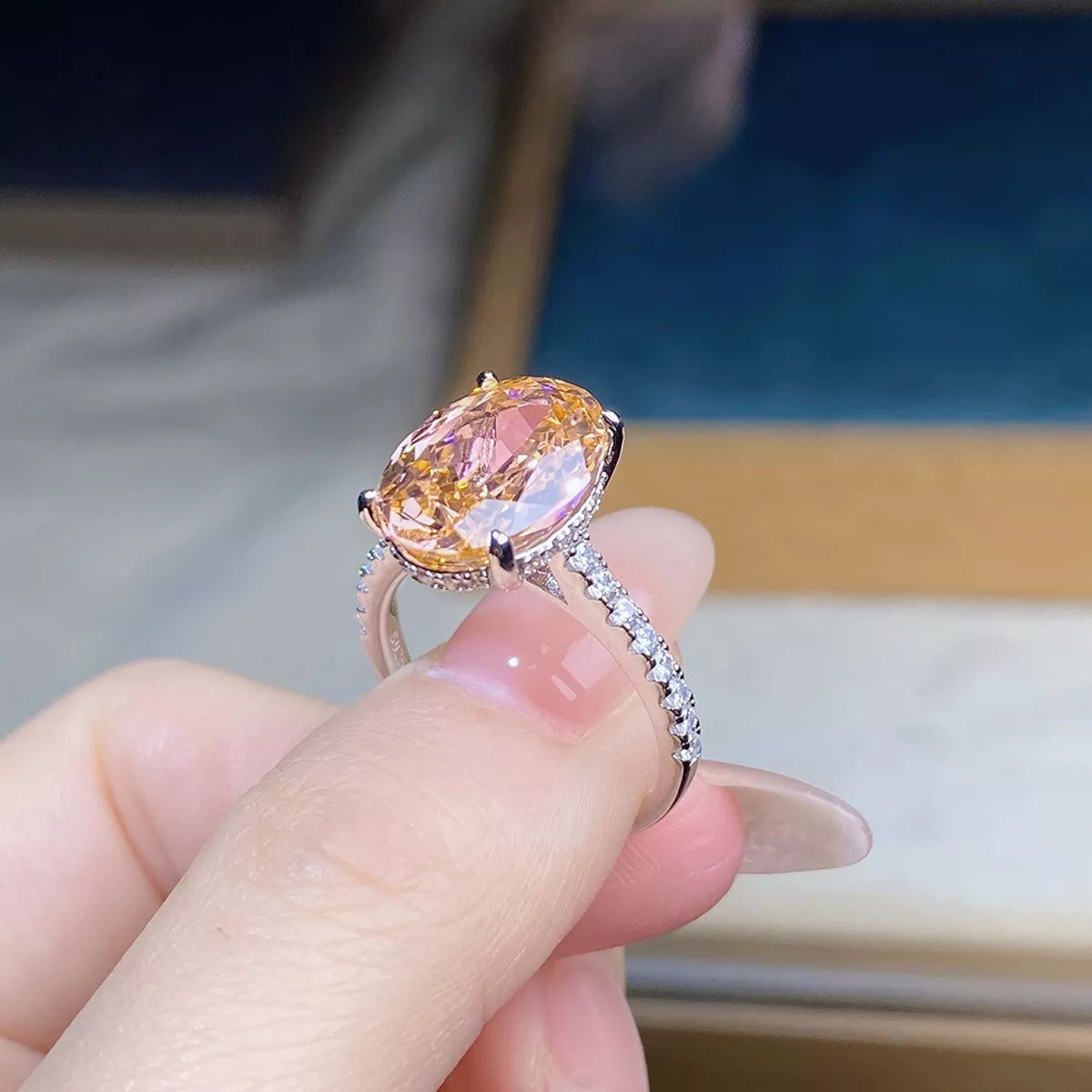 Pink oval center stone ring worn on a hand, viewed from above