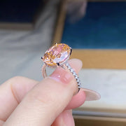 Pink oval center stone ring worn on a hand, viewed from above